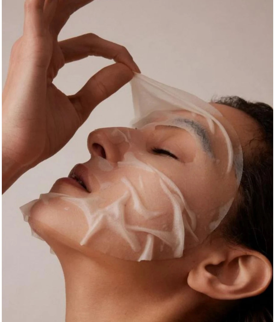 Woman receiving a sheet mask facial care application
