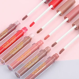 Various lip gloss and applicators on a pink surface.