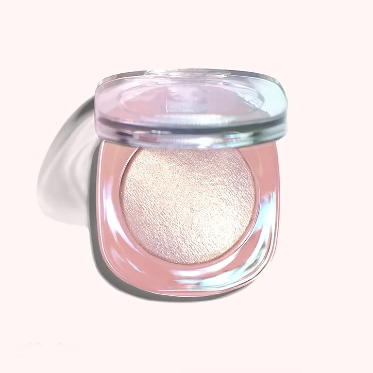 A round, open jar containing a shimmery cream highlighter, with a clear lid.