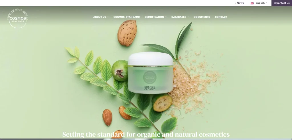 Barattolo di cosmetici biologici Cosmos con ingredienti naturali su sfondo verde.