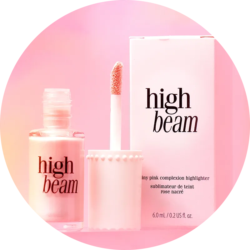 Open bottle of High Beam complexion highlighter with a box against a pink background.