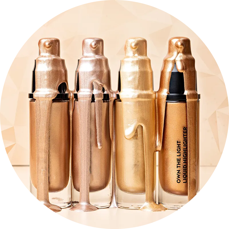 Four liquid highlighter bottles with dripping metallic colors in a gradient from gold to bronze, with the label 'Own the Light Liquid Highlighter' on the rightmost bottle.