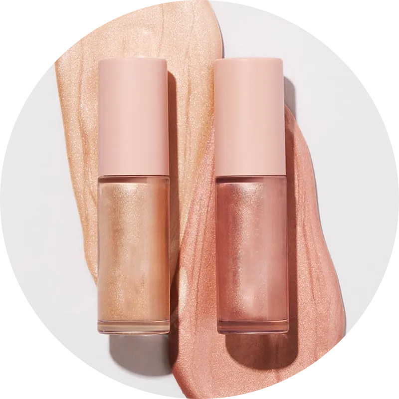 Two bottles of liquid highlighter with peach and gold tones neatly placed on a surface