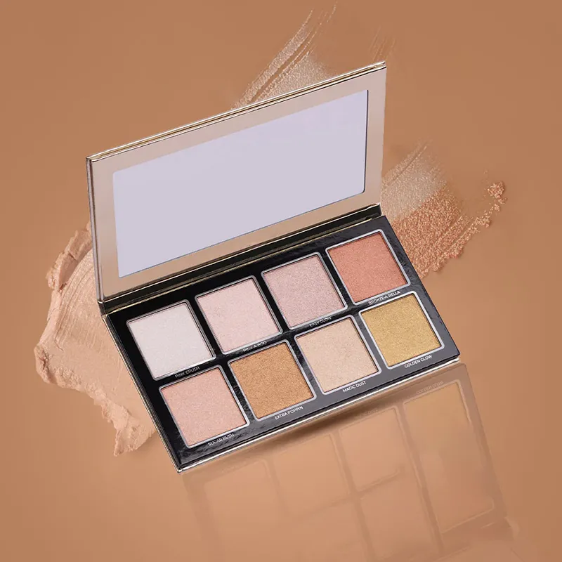 An open luxury highlighter makeup palette with eight different shades on a brown background.