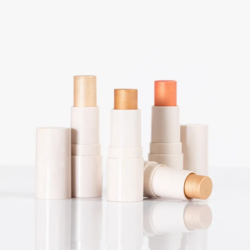 Three open makeup sticks in light neutral shades with matching caps.