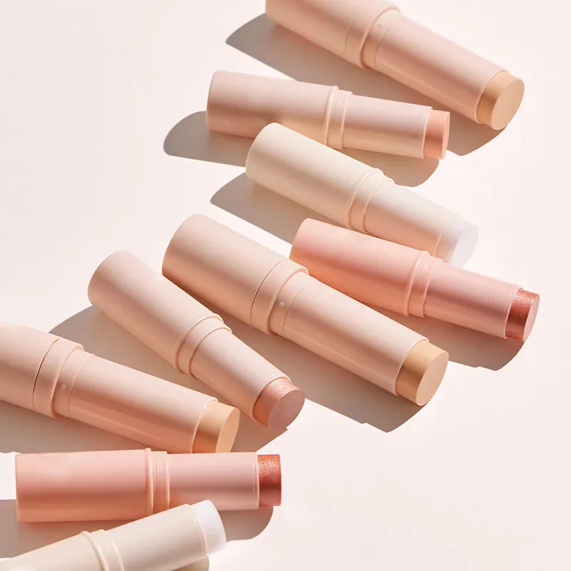 Assorted makeup sticks in pastel shades arranged on a light surface.