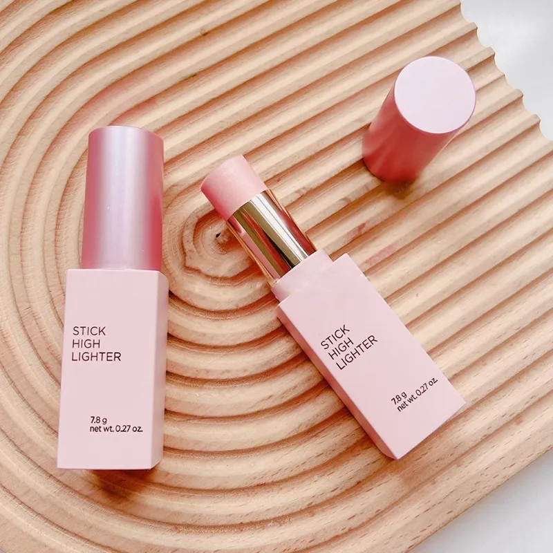 Two stick highlighters in a pink color on a wooden surface, one open showing the product.