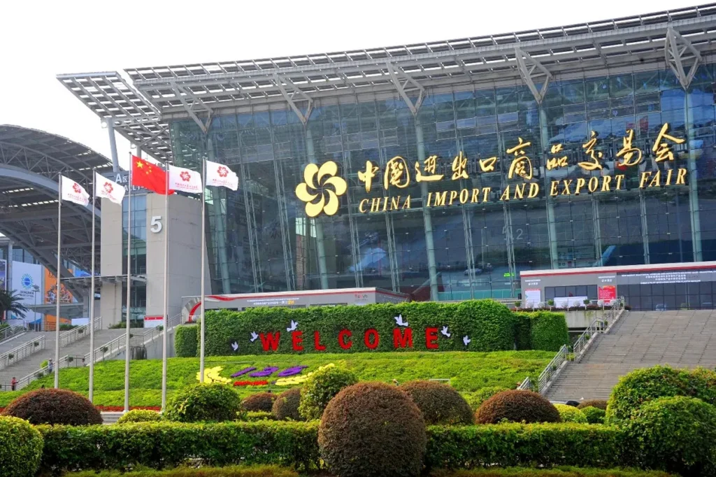 The entrance of the China Import and Export Fair showing flags, a welcome sign, and the main building.
