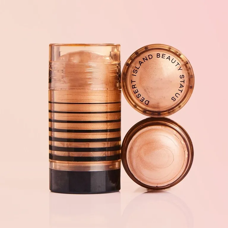 A beauty stick with a cylinder shape and textured cap in metallic hue labeled 'Desert Island Beauty Status'.