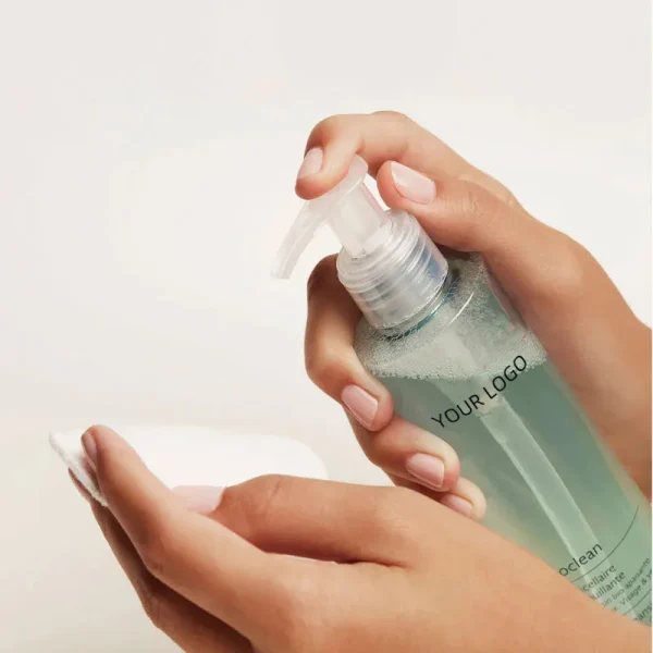 A person using a liquid soap dispenser with clear liquid soap.