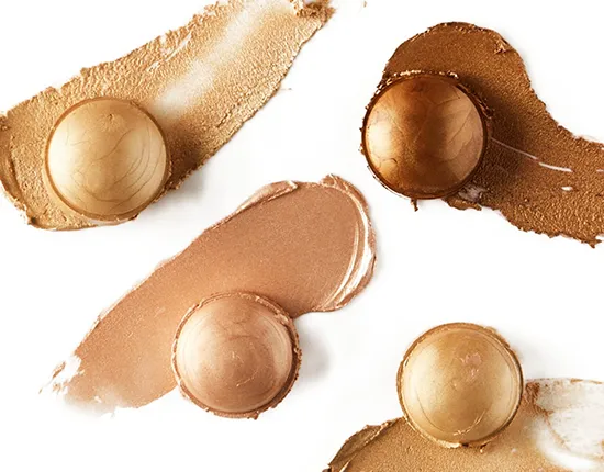 Various shades of highlighter makeup with creamy textures and shine shown on a white background.