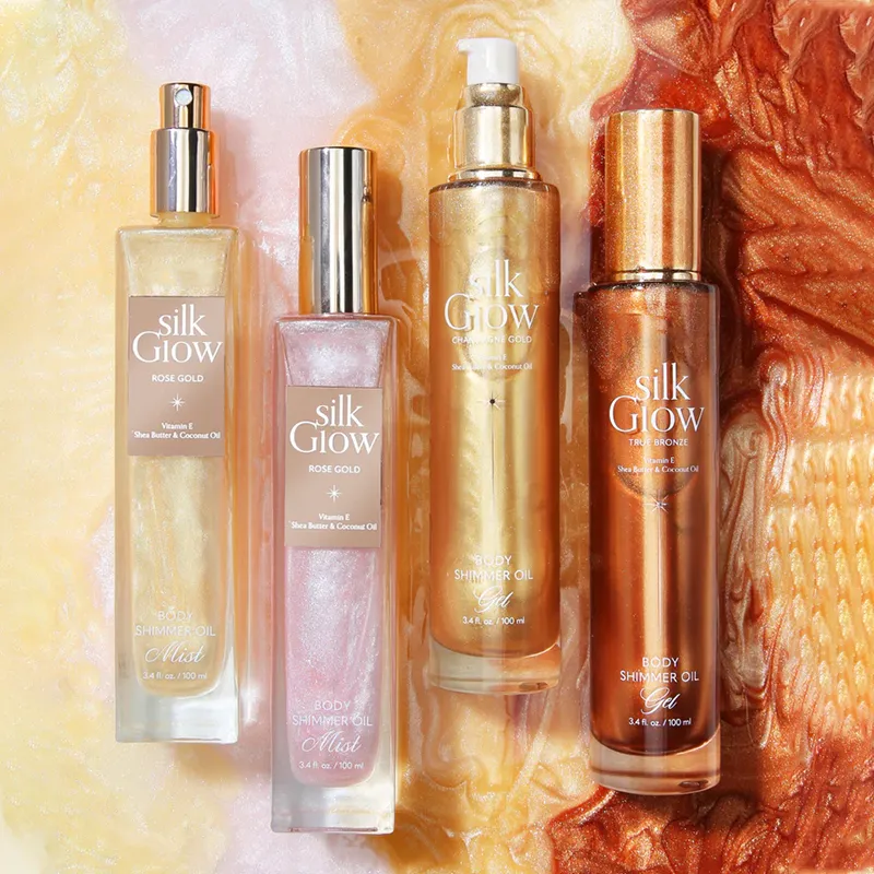 Four bottles of Silk Glow body shimmer oils in different colors on a textured background.
