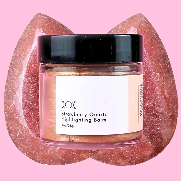 A jar of Strawberry Quartz Highlighting Balm with a pink background and crystal texture.