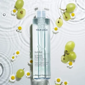 A bottle of VinoClean Micellar Cleansing Water surrounded by grapes and chamomile flowers on a rippled water surface