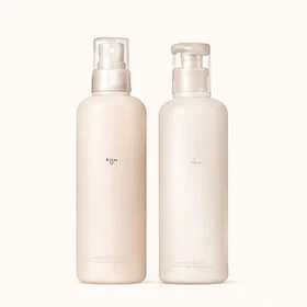 Two minimalist white skincare bottles with pump tops on a neutral background.