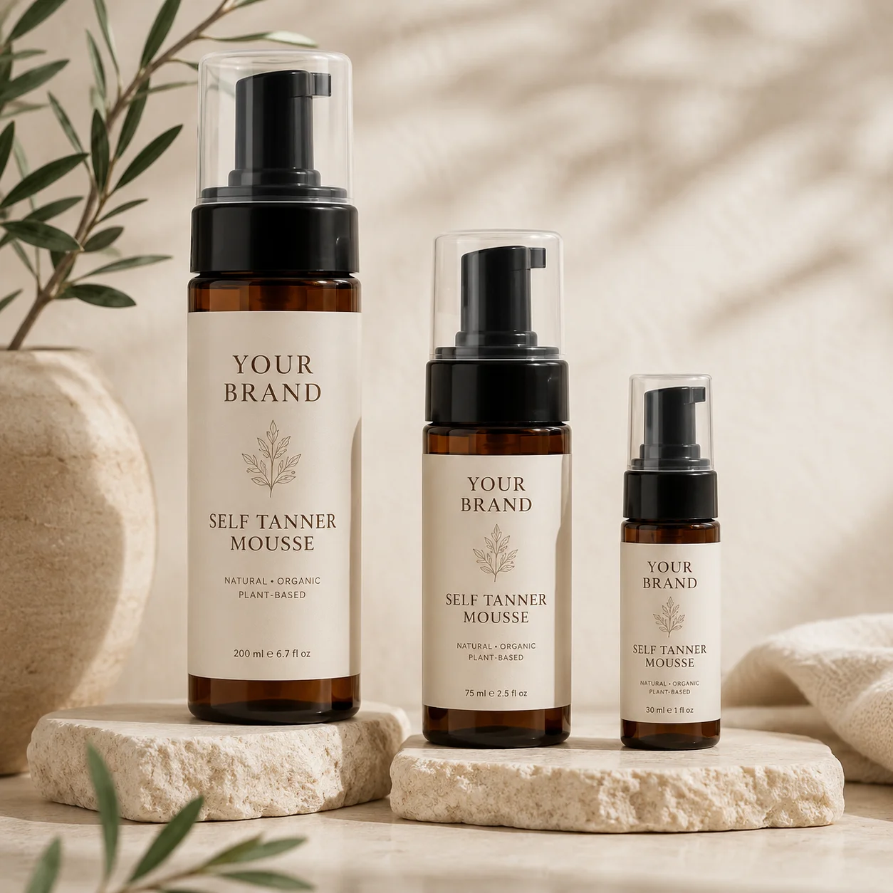 Three bottles of self-tanner mousse labeled 'Your Brand' in different sizes, displayed on natural stone slabs with a minimalist and organic background.
