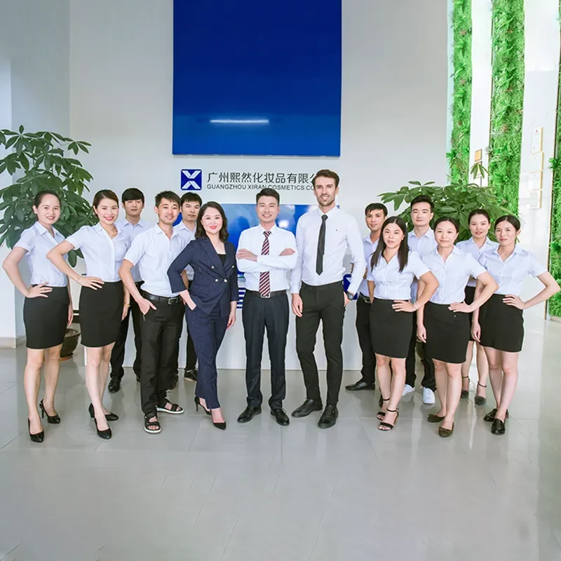 Group photo of the Guangzhou Xiran Cosmetics team in an office setting with a blue sign in the background.